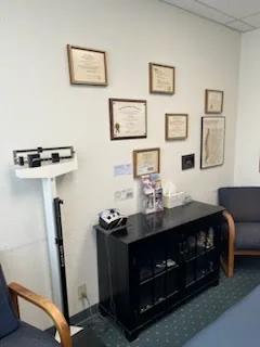 Framed diplomas and certificates on the office wall above a black cabinet