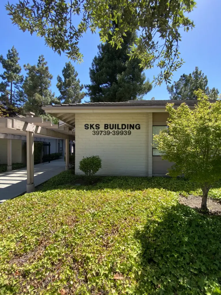 The SKS Building sign, numbers 39739 to 39939, on a lawn under tall pines